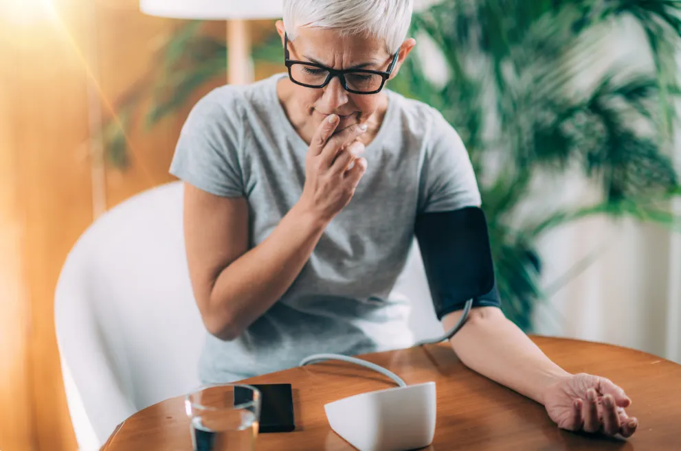 Woman using blood pressure monitor with smartphone