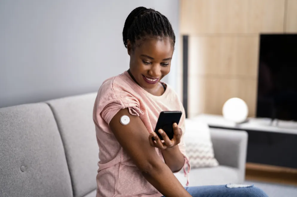 Woman with continuous glucose monitor holding smartphone