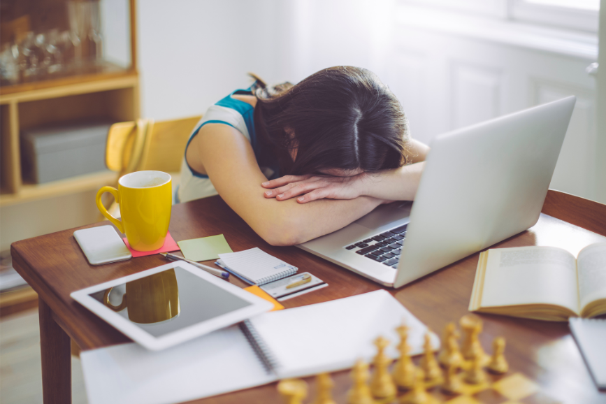 Woman with head down on desk with laptop and mug