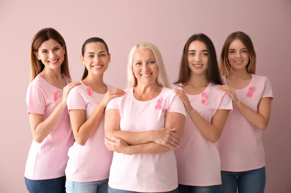 Women of different ages with pink ribbons on color background