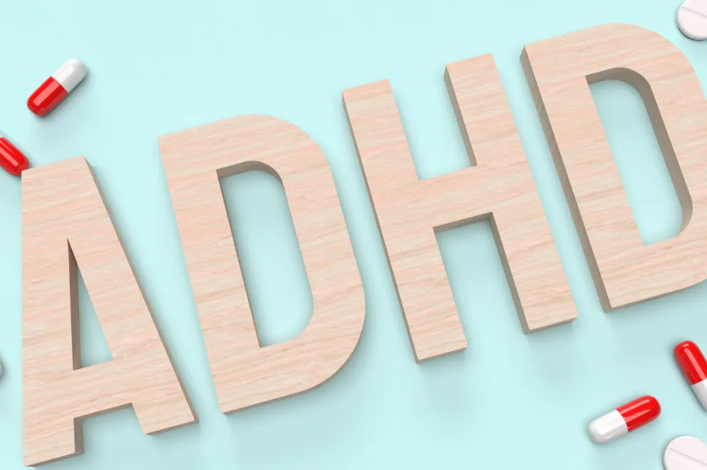 Wood Letters ADHD on Blue Background with Red and White Pills
