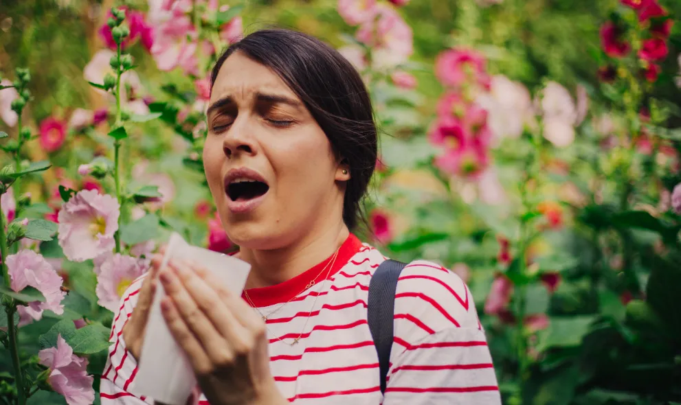 Young woman sneezing around flowers